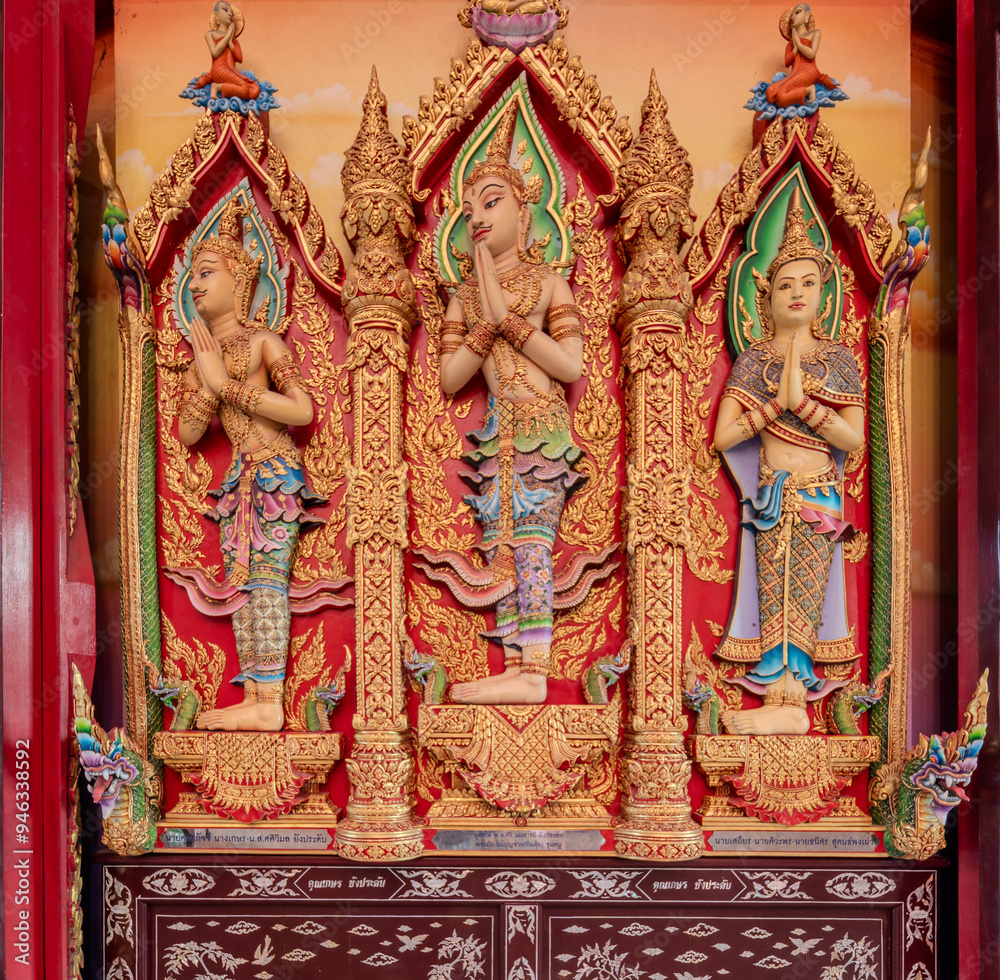 Obraz premium Intricately carved wooden statues of deities in traditional attire at a temple in Thailand during daylight
