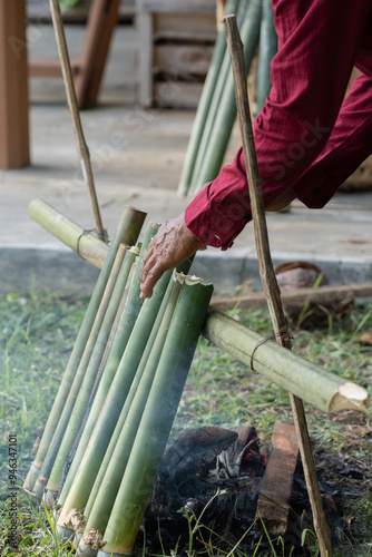 The process of making lemang, a food that is quite well-known in Malaysia and Indonesia. A man is making lemang, a food made from sticky rice that is put into bamboo lined with banana leaves