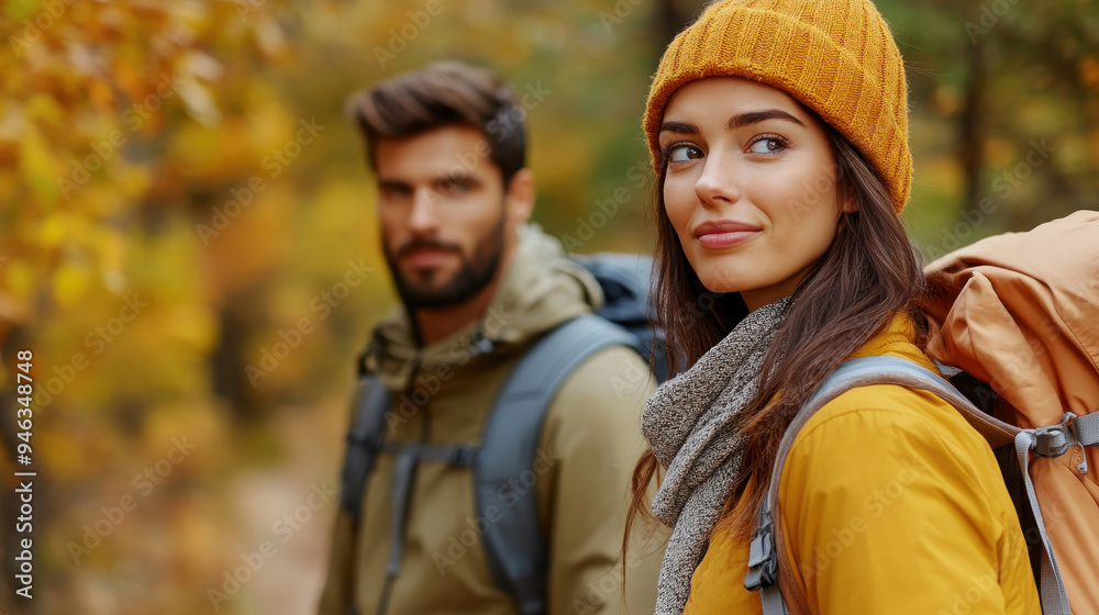 Young couple hiking in autumn forest, wearing warm clothing, backpacks, and enjoying the beautiful fall scenery Young couple hiking in autumn forest, wearing warm clothing, backpacks, and enjoying the beautiful fall scenery