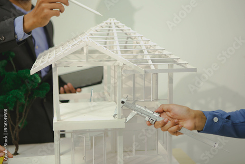 Engineers are discussing house construction plans, reviewing blueprints, assessing materials, and evaluating project timelines. They address safety standards, budget constraints, and design