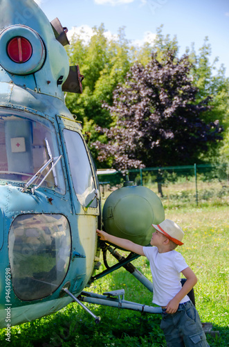 Funny little boy traveler sits near the landing gear of the plane photo