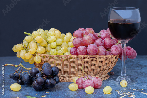 Obraz na płótnie Black grapes on a table, yellow and red grapes in a basket and a glass of red wine on the table w salonie
