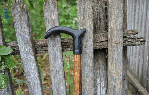 old walking stick near wooden fence close-up. selective focus. old age and loneliness concept photo