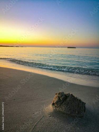 Tramonto su una spiaggia del Salento. I resti di un castello di sabbia proiettano la loro ombra sul bagnasciuga.  photo