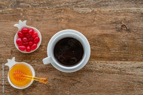 Cup of coffee, fresh honey, pomegranate marmalade candies for Jewish holiday Rosh Hashanah over wooden background. Top view. photo