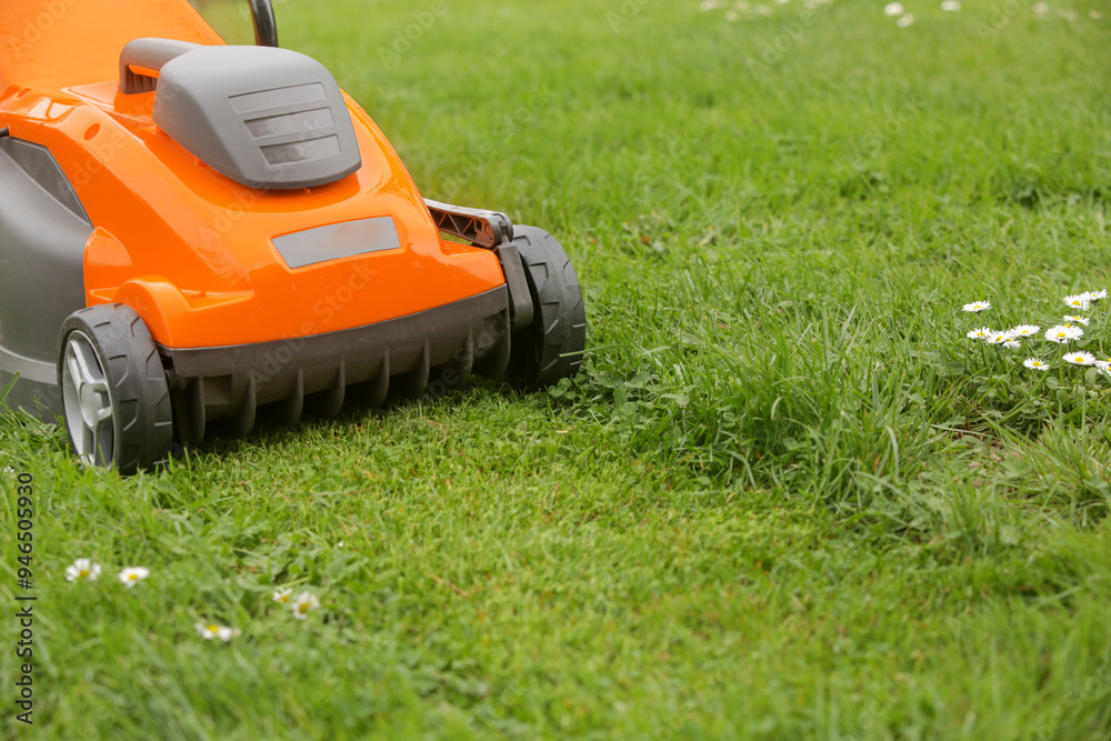 Orange lawn mower on the spring green grass in the yard Orange lawn mower on the spring green grass in the yard