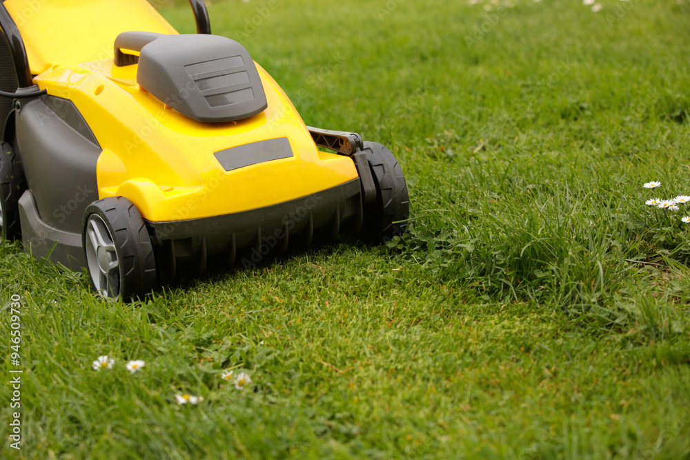 Yellow lawn mower on the spring green grass in the yard Yellow lawn mower on the spring green grass in the yard