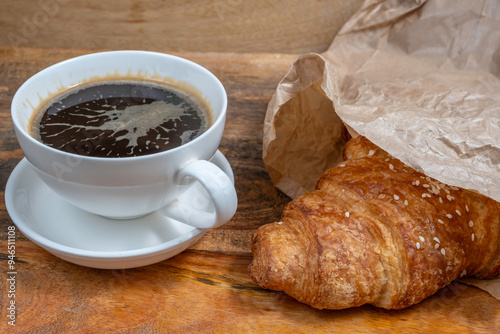 Freshly baked croissant and cup of coffee for tasty breakfast.
