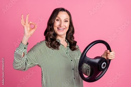 Photo of nice aged woman wheel okey symbol wear striped shirt isolated on pink color background photo