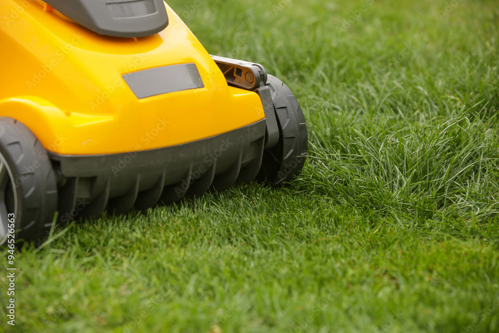 Yellow lawn mower on the spring green grass in the yard Yellow lawn mower on the spring green grass in the yard