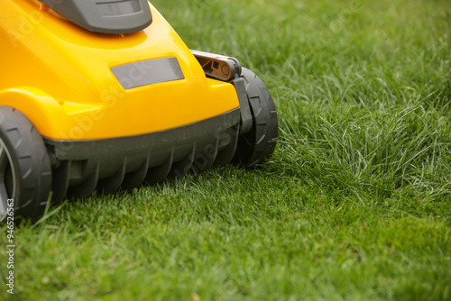 Yellow lawn mower on the spring green grass in the yard