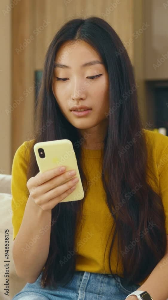Beautiful asian young woman use phone sitting on sofa at home. Social media text email enjoy distant communication. Close up. Slow motion Beautiful asian young woman use phone sitting on sofa at home. Social media text email enjoy distant communication. Close up. Slow motion