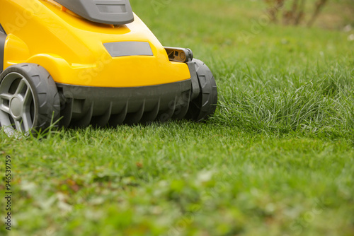 Yellow lawn mower on the spring green grass in the yard