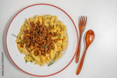 Ground beef pasta on ceramic plate served with fresh thyme. Top view.