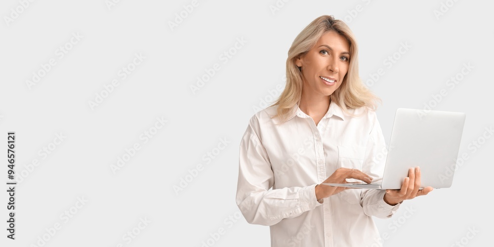 Fototapeta premium Mature businesswoman with laptop on light background with space for text