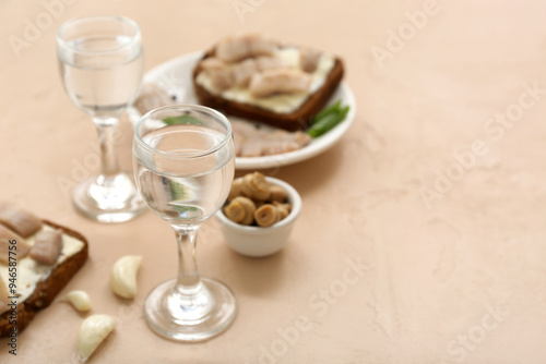 Shots with cold vodka and snacks on beige background