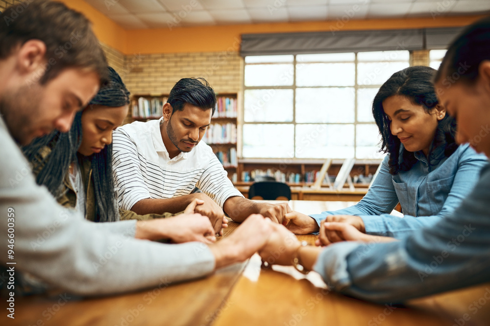 Obraz premium Students, people and praying together for study, faith and university exam with community in library. Friends, diversity and holding hands on campus for college test, education and Christian society