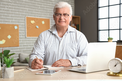 Senior man with laptop writ...