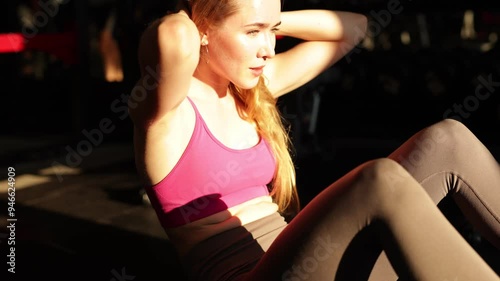 Girl doing abdominals exercises in the gym. Sportswoman in pink top doing workout in the gym exercises for ABS