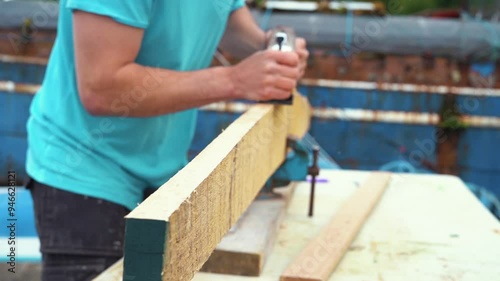 Carpenter using hand plane on white oak boatbuilding photo