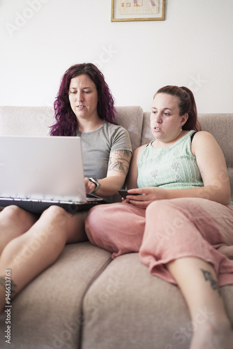 Two women sitting on a couch looking at a laptop