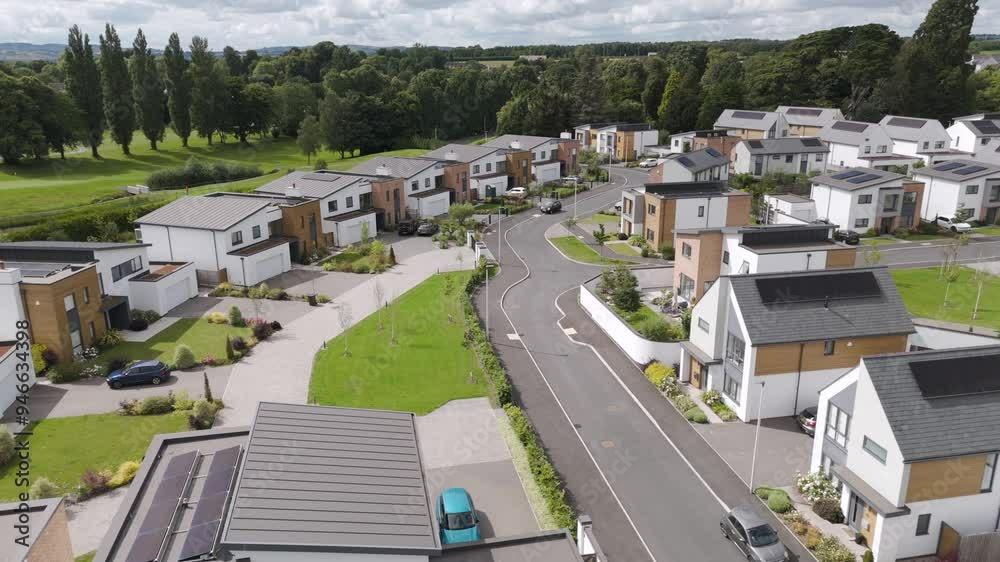 Aerial establishing view of newly built luxury eco-friendly homes with solar panel roofs, surrounded by lush greenery in a modern residential neighborhood
