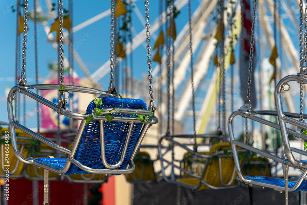 row of swings with green and blue seats hanging from a chain row of swings with green and blue seats hanging from a chain