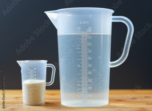 Obraz na plátně A measuring cup with water and a small measuring cup with milk powder
