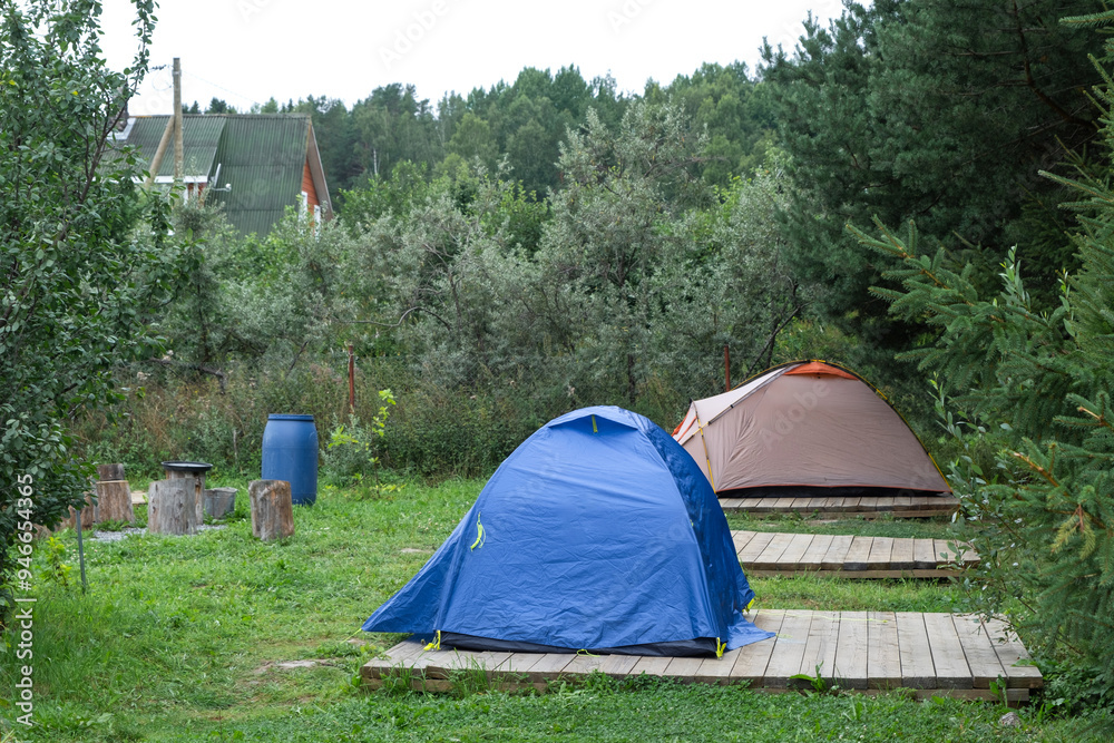 Installed tourist tent in a camping in nature in the forest. Domestic tourism, active summer holidays, family adventures. Ecotourism, sport, hike. Copy space, mock up Installed tourist tent in a camping in nature in the forest. Domestic tourism, active summer holidays, family adventures. Ecotourism, sport, hike. Copy space, mock up