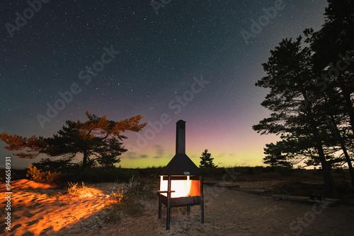 Landscape night photo, sea sand beach Perakula with grill places and burning fire. Starry sky and northern lights. photo