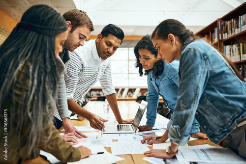 Library, university student and group work with laptop for research, teamwork and collaboration on campus. People, classmates and college learner with document or notes for test, study and exams