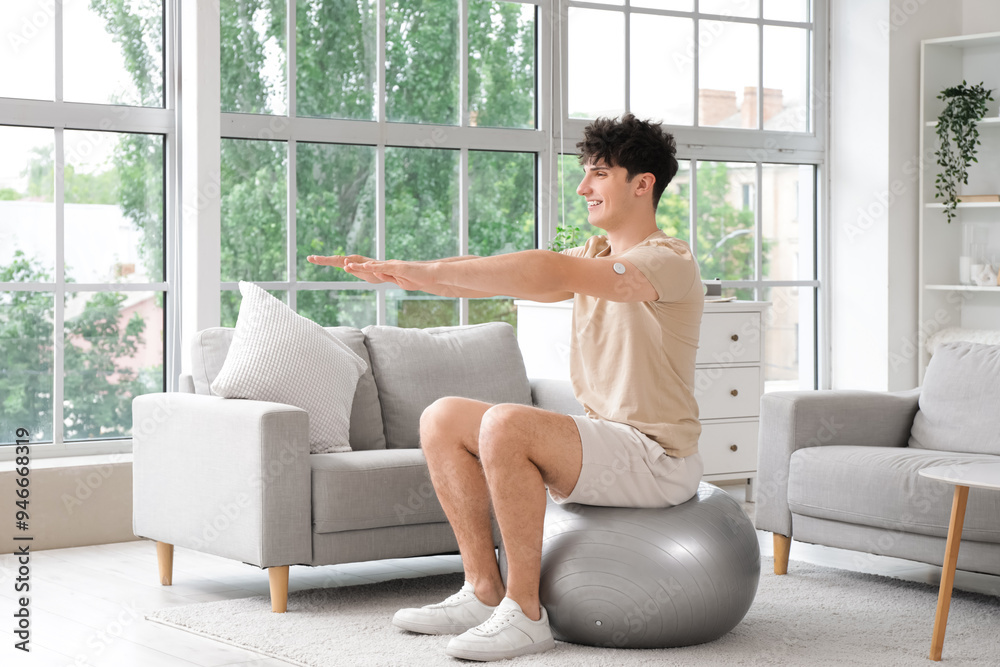 Diabetic young man with glucose sensor training on fitball at home Diabetic young man with glucose sensor training on fitball at home