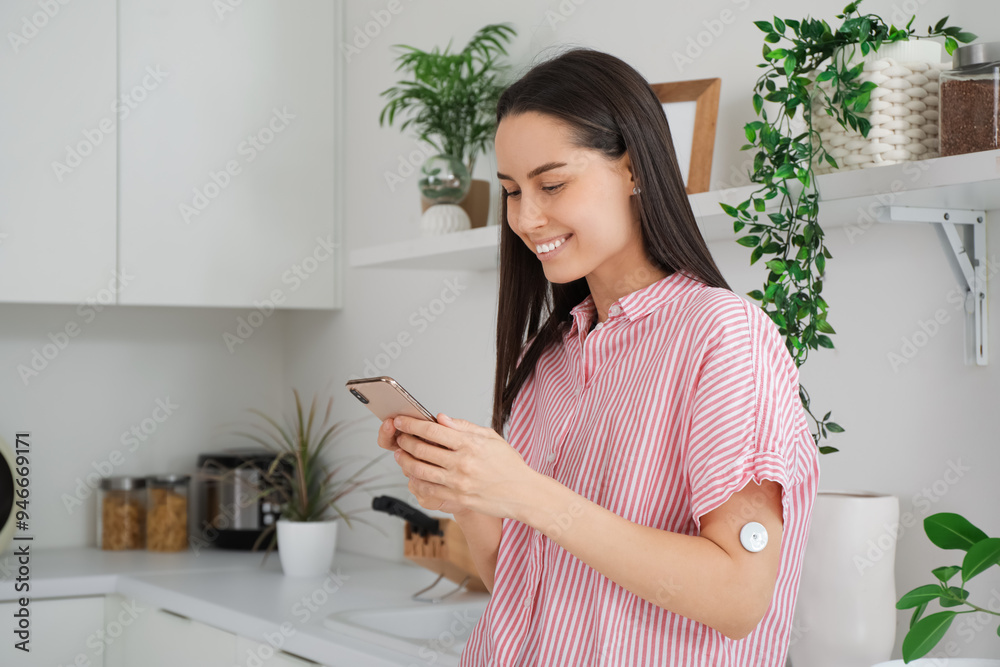 Diabetic young woman with glucose sensor and mobile phone measuring blood sugar level in kitchen Diabetic young woman with glucose sensor and mobile phone measuring blood sugar level in kitchen