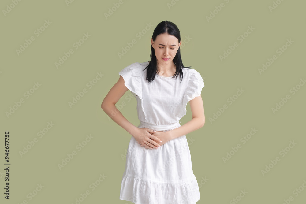 Young woman suffering from severe abdominal pain on green background Young woman suffering from severe abdominal pain on green background