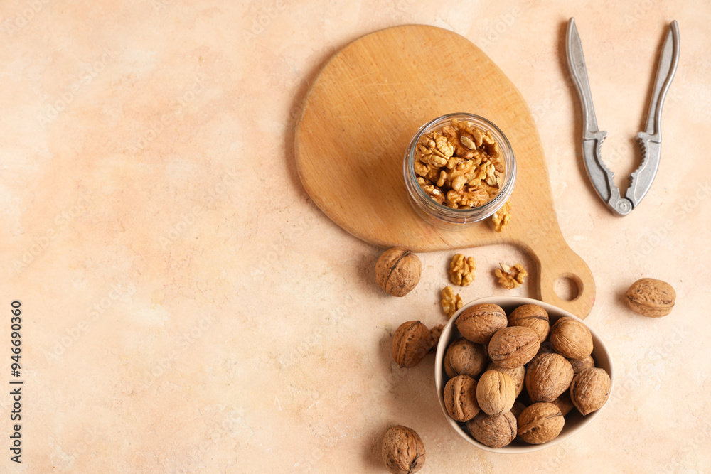 Bowl and jar with tasty walnuts on beige background Bowl and jar with tasty walnuts on beige background