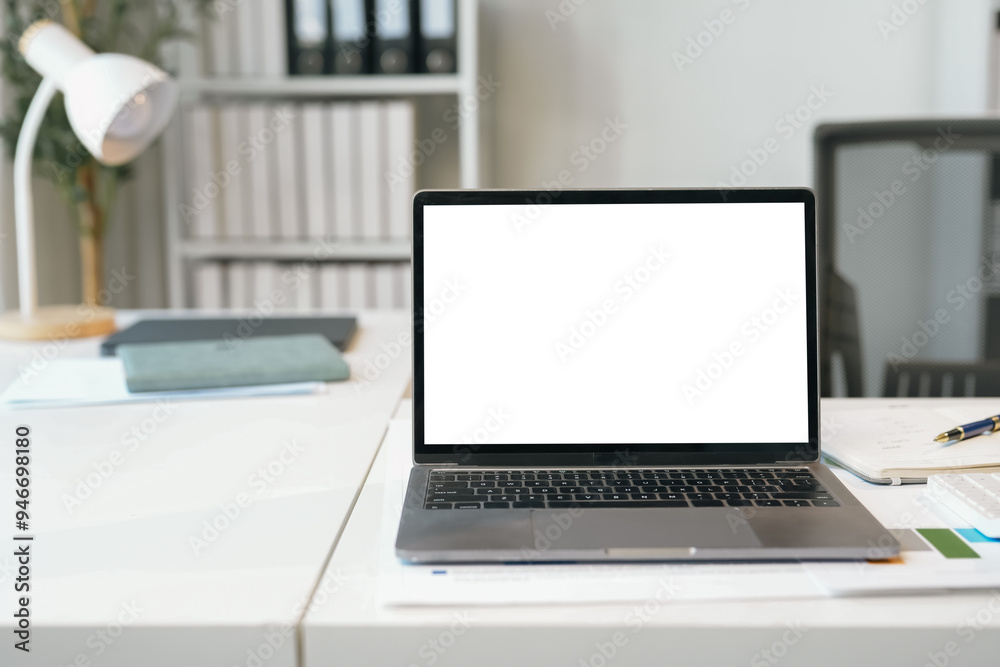 Modern laptop showing blank screen standing on desk with various stationery in bright office Modern laptop showing blank screen standing on desk with various stationery in bright office