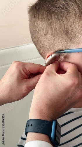 A doctor puts a hearing aid with a custom earmold on the ear of a 10-year-old boy. Wearing hearing aids as a child photo