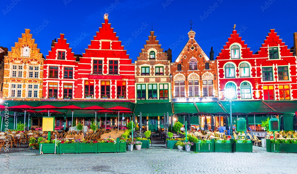 Fototapeta premium Bruges, Belgium: Night view of the colored houses in the north side of Grote Markt with enchanting street cafes and restaurants, West Flanders