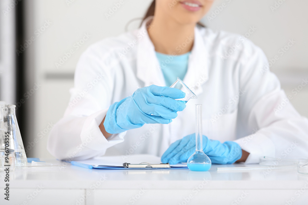 Happy female young scientist with professional glassware and clipboard examining water quality in research laboratory, closeup Happy female young scientist with professional glassware and clipboard examining water quality in research laboratory, closeup