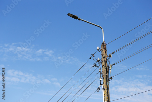 Concrete pole streetlight and a carrier for high voltage cables with ceramic insulators. Village electrical infrastructure. Power transmission background. Voltage wire tower. High voltage supply. photo