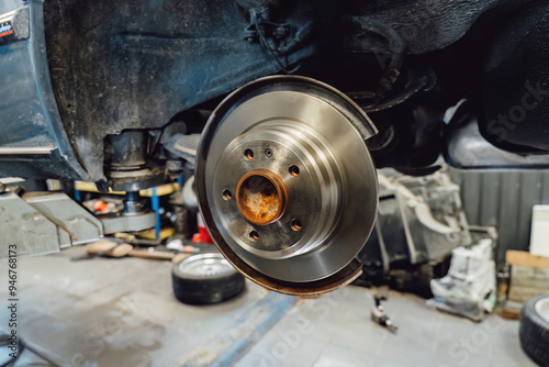 The rim is removed showing the rotor and caliper. Disc brake on car in process of new tire replacement