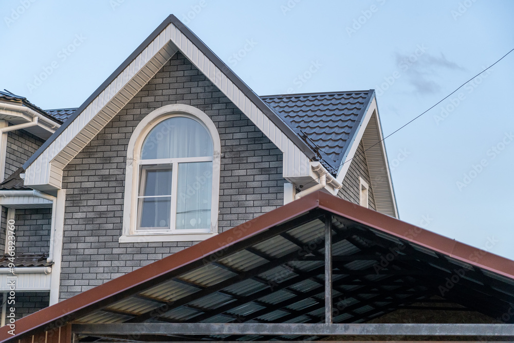 A charming house features a sloped roof, detailed facade, and expansive windows, showcasing suburban living at twilight A charming house features a sloped roof, detailed facade, and expansive windows, showcasing suburban living at twilight