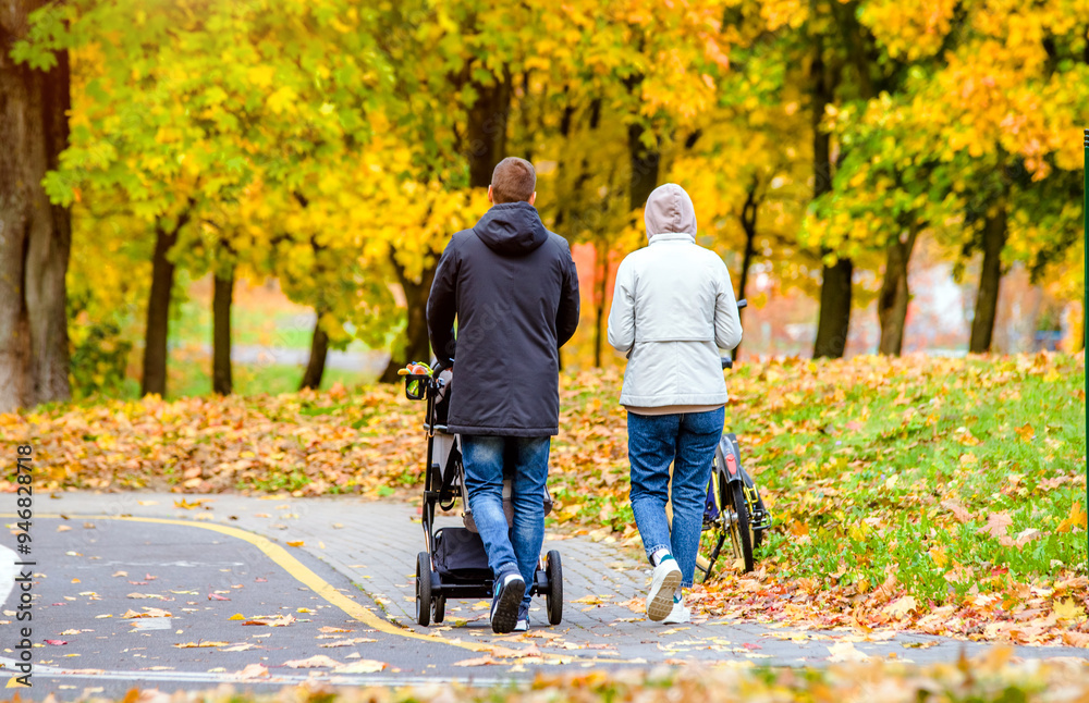 Obraz premium A married couple rolls a baby stroller in a city Park 