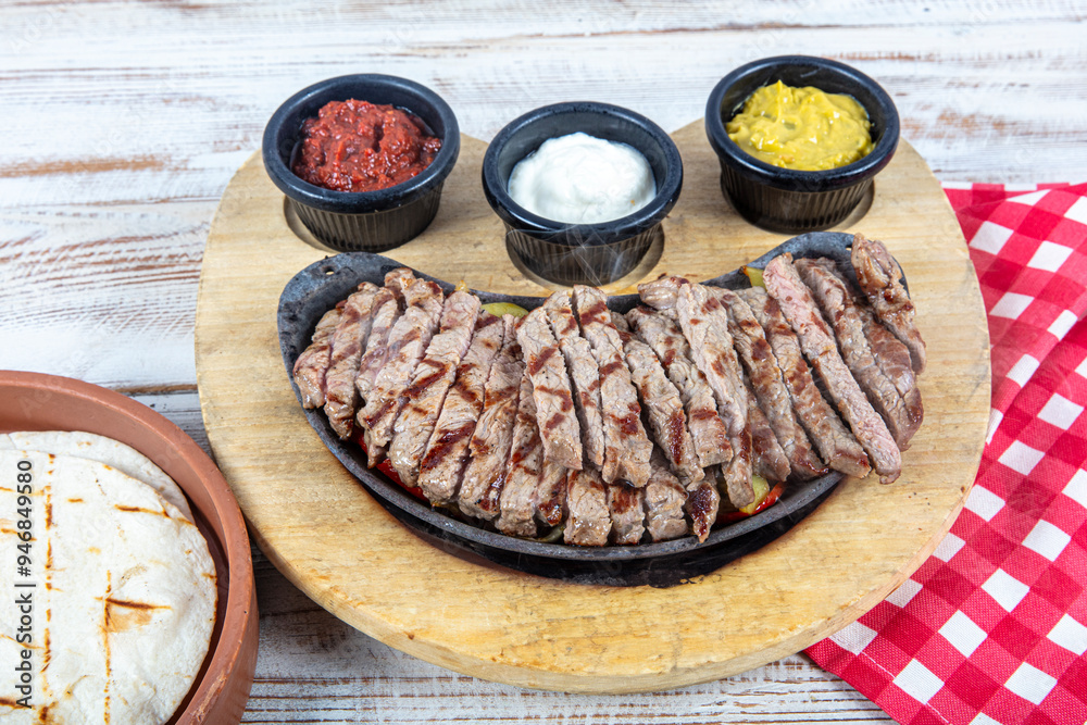 Beef Fajitas with colorful bell peppers in pan and tortilla bread and sauces. Beef Steak Fajitas with tortilla mix pepper, onion and avocado on wooden board. Beef Fajitas with colorful bell peppers in pan and tortilla bread and sauces. Beef Steak Fajitas with tortilla mix pepper, onion and avocado on wooden board.