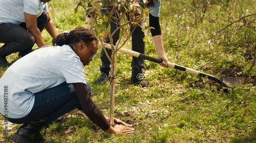 Team of volunteers planting trees in the forest by digging holes in the ground, giving life to the natural habitat and ecosystem. Activists doing voluntary work to save the planet. Camera A.