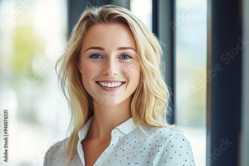 Free Download Portrait of a Smiling Blonde Woman in a Casual Shirt by an Office Window with Blurred Background and Bright Light, Captured Using a Canon EOS R5 Camera for a Professional Look - GFXLoad