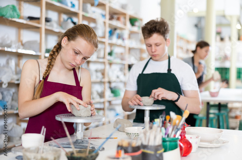 Pottery lesson - teenagers intently create dishes from clay photo