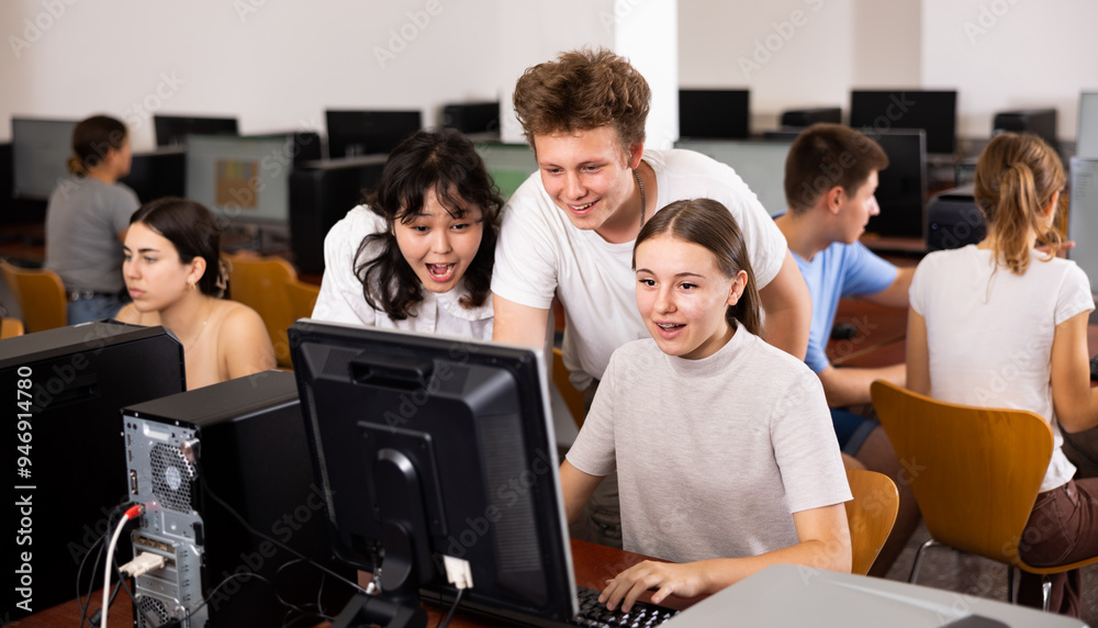 Fototapeta premium Portrait of multinational young students group emotionally reacting while studying at pc in college computer class