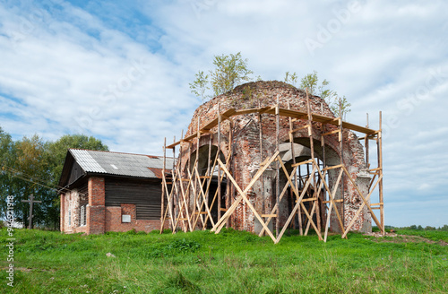 Restoration, wooden scaffolding around the ruins of an ancient christian church in Nikolskoye village, Vologda region, Russia photo