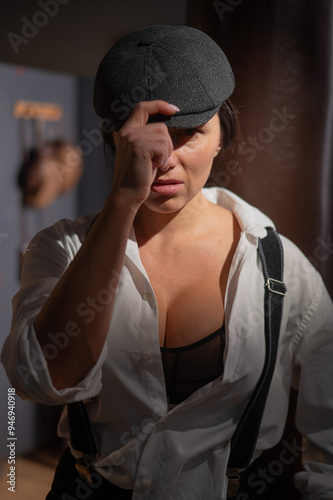 Caucasian woman in a Peaky Blinders style men's suit posing in a retro gym.